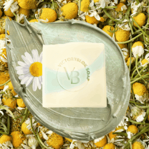VICTORYBLOKS CHAMOMILE COTTAGE soap bar in soft light green, set against a background of chamomile flowers and a blue sky. Made with olive oil, coconut oil, French green clay, and chamomile essential oil.