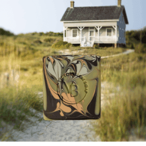 VICTORYBLOK Cottage Clay Soap Bar with vibrant swirls of brown, green, and orange clays, set against a sandy beach cottage background. Crafted with olive oil, coconut oil, lemon and ylang ylang essential oils for a beautifully scented, natural cleanse.