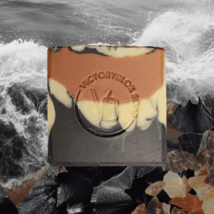 VICTORYBLOKS Frankincense Wildwood soap bar with bold layers of black activated charcoal, cream, and red clay, standing on charcoal and frankincense, set against grey sea waves. Made with olive oil, coconut oil, red clay, activated charcoal, and frankincense essential oil for a soft, foamy, earth-healing cleanse.